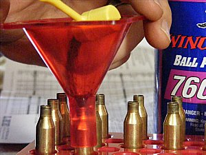 Charging a .243 rifle case with powder using a Lee Precision Powder Dipper and Lee Precision Powder Funnel